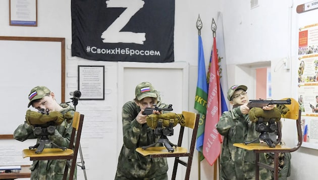 „Übung“ mitten im Klassenzimmer. Das „Z“ ist ein russisches Militärzeichen und ein Symbol für die Unterstützung des Angriffskrieges. Darunter steht: „Wir lassen die Unseren nicht im Stich.“  (Bild: Илья Наймушин / Спутник / РИА Новости / Profimedia)