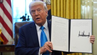 Trump hält das entsprechende Dekret in die Kameras.