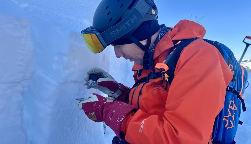 Butschek überprüft mit der Lupe die Schneebeschaffenheit. (Bild: Maximilian Kronberger)