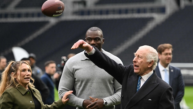 King Charles was shown how to throw the ball properly. (Bild: Photo by Eddie MULHOLLAND / POOL / AFP)