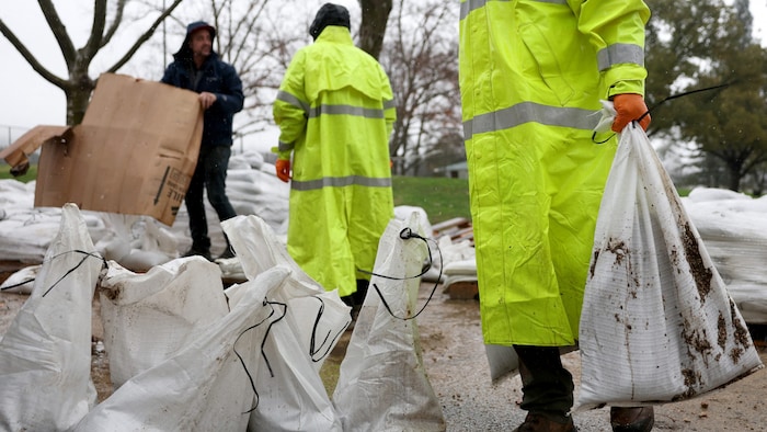 Gemeindemitarbeiter versuchen den Wassermassen mit Sandsäcken Herr zu werden.