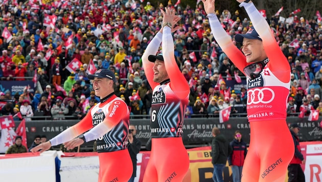 Winner Franjo van Allmen, third-placed Alexis Monney and second-placed Marco Odermatt (from left) celebrate the Swiss triple victory. (Bild: APA/AFP/Maxime Schmid)