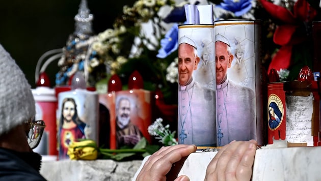 Vor dem Gemelli-Krankenhaus in Rom stellten Gläubige Kerzen für Papst Franziskus auf. Atemkrise, mit der der Papst am Samstag zu kämpfen hatte, sei am Sonntag weitgehend abgeklungen, hieß es am Sonntag. (Bild: AFP/FILIPPO MONTEFORTE)