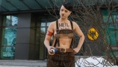 Eine Femen-Aktivistin posiert in Lederhose für die Kameras. Zuvor hatte sie nahe der Deutschen Botschaft (im Hintergrund) ein Hakenkreuz an die Wand gemalt. (Bild: EPA, Krone KREATIV)