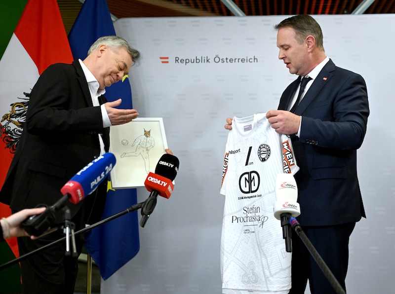 Andreas Babler presented his predecessor Werner Kogler with two gifts: a sports outfit and a drawing of a lynx. (Bild: APA/ROLAND SCHLAGER)