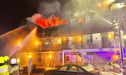 Feuerwehrleute löschen das Feuer am Dach des Wohnhauses.