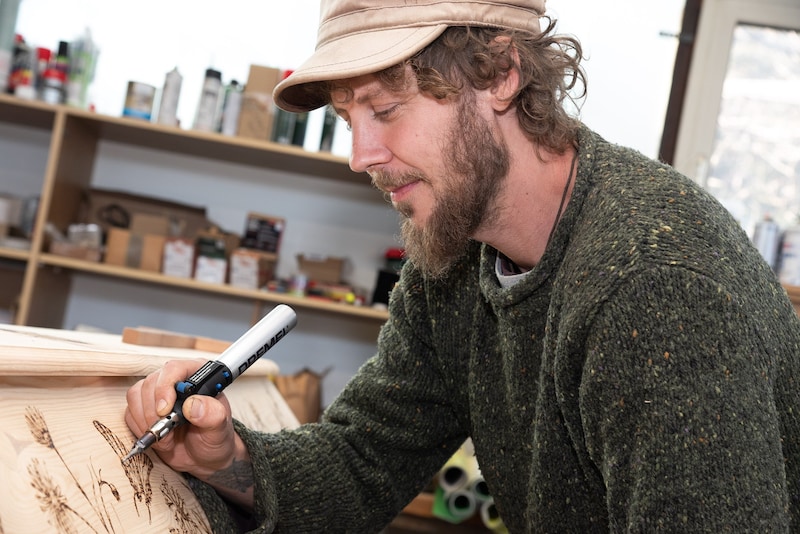 Stefan Knöpfer mills motifs into the wooden coffin using his own burning rod. Butterflies and birds are particularly popular. (Bild: Seebacher Doris)