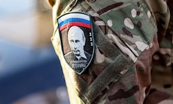 Ein russischer Soldat trägt das Portrait von Putin auf seinem Arm.