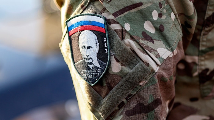 Ein russischer Soldat trägt das Portrait von Putin auf seinem Arm.