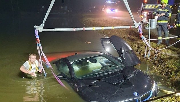 Dem Feuerwehrmann im eisigen Teich war sichtlich kalt, als er den versunkenen BMW-Hybrid sicherte. (Bild: FF Altenfelden)