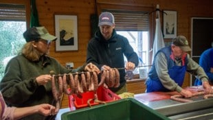 Opa Matthias portioniert die Würstel (re.), Enkel Max hängt sie auf.