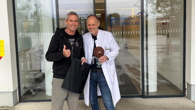 Michael Konsel leaving the clinic with his doctor Michael Gabel. The ex-team goalkeeper presented him with one of his "Konsel mugs" out of gratitude. (Bild: Privat)