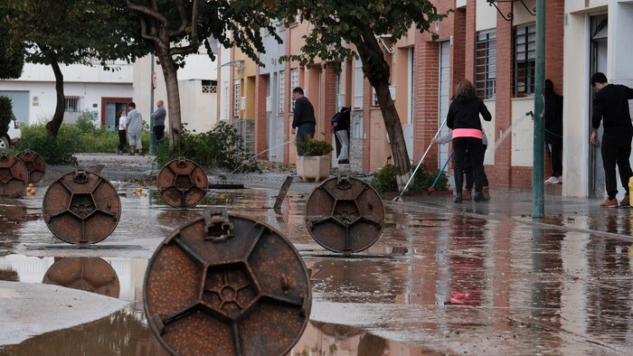 Anwohner befreien die Straßen von Schlamm nach schweren Regenfällen in Campanillas, Málaga.