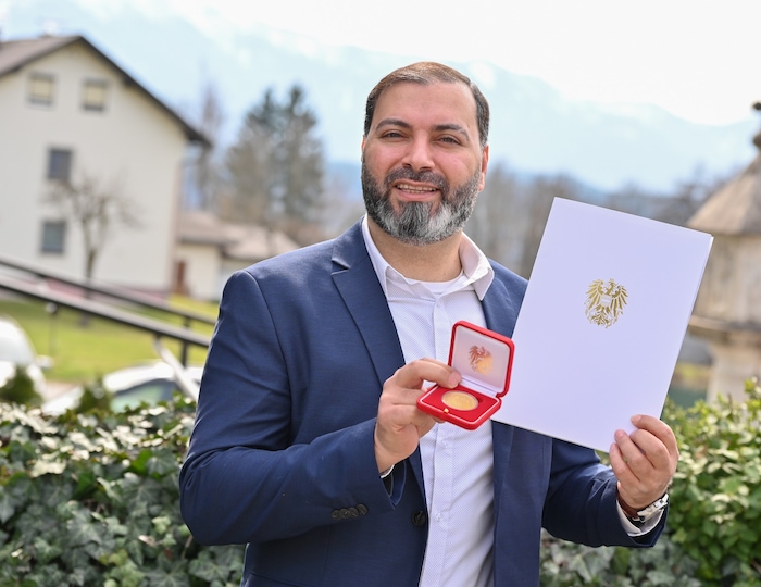 Stolz zeigt A. die Ehrengoldmünze des Bundeskanzlers.