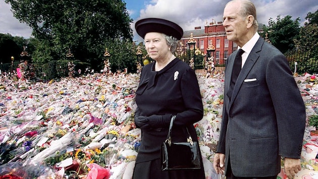 Königin Elisabeth II. und ihr Prinzgemahl. Im Hintergrund: Blumen, die vor Dianas Londoner Wohnsitz Kensington Palace abgelegt wurden. (Bild: Krone KREATIV/APA Picturedesk)