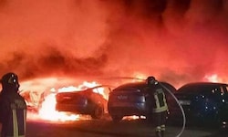 Feuerwehrleute beim Löschen des Brandes die auf einem Parkplatz eines Tesla-Händlers in Rom.