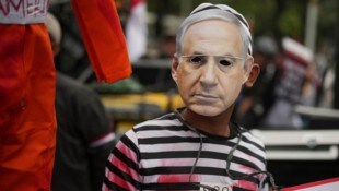 Ein Demonstrant im Gefangenenkostüm und Netanyahu-Maske