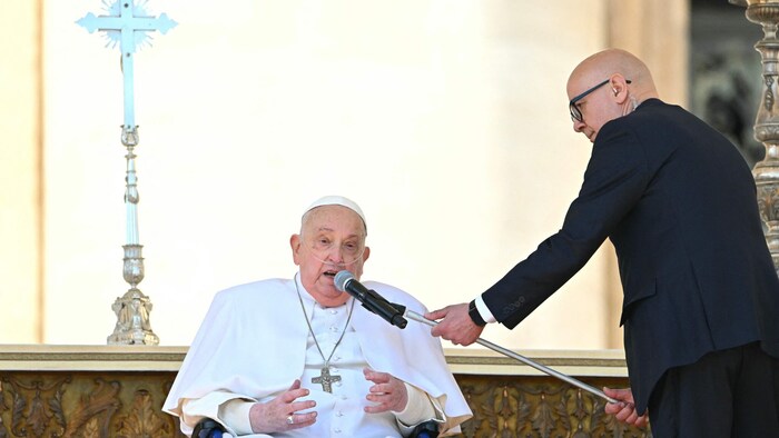 Ein Mitarbeiter hilft dem Pontifex, vor der Menge zu sprechen.