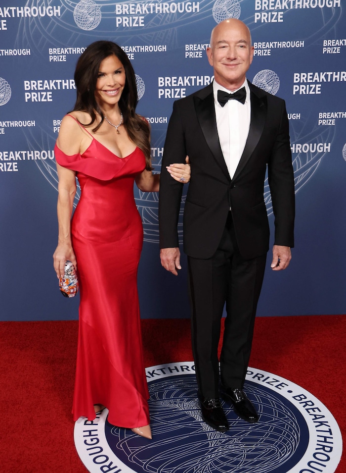 Lauren Sanchez im Kleid von Galliano, ein Handtäschchen im Form eines Astronauten in der Hand und ihren Mega-Verlobten am Arm ....