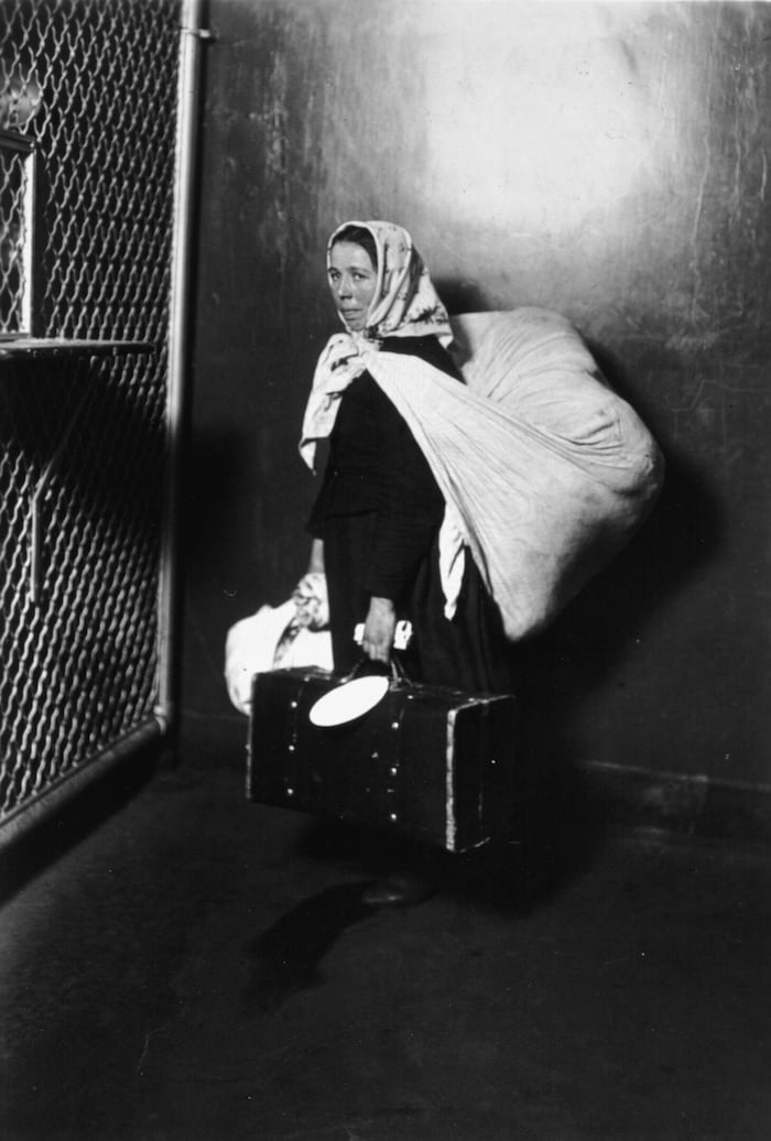 Eine Migrantin trägt ihr gesamtes Hab und Gut. Ellis Island, 1905