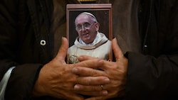 Eine Katholikin hält ein Bild des Papstes in den Händen, als sie nach seinem Tod die Messe in San Jose de Flores in Buenos Aires besucht. (Bild: AFP/LUIS ROBAYO)