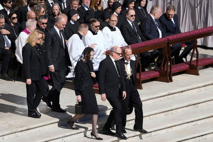 Fürstin Charlène und Fürst Albert auf dem Weg zu ihren Plätzen. Die Fürstin, bekannt für ihren minimalistischen Stil, kombinierte ein schlichtes Etuikleid mit einem leichten Schleier .