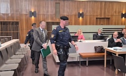 Der Angeklagte wird von der Justizwache zur Anklagebank vorgeführt.