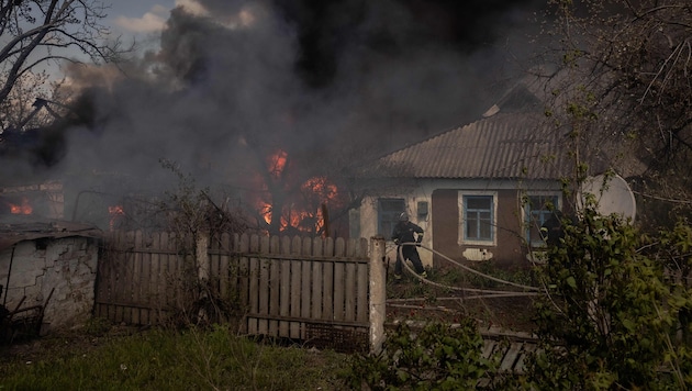 Ukrainische Feuerwehrleute bei Löscharbeiten nach einem Angriff im Dorf Tschernihiwka im Bezirk Pokrowsk, etwa 25 Kilometer nördlich der Bezirkshauptstadt Donezk (Bild: AFP/ROMAN PILIPEY)