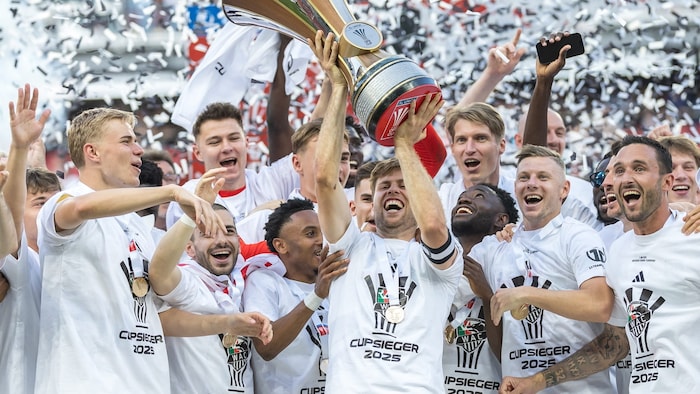 Kapitän Dominik Baumgartner stemmt die Cup-Trophäe in die Höhe, seine Mannschaftskollegen jubeln ...