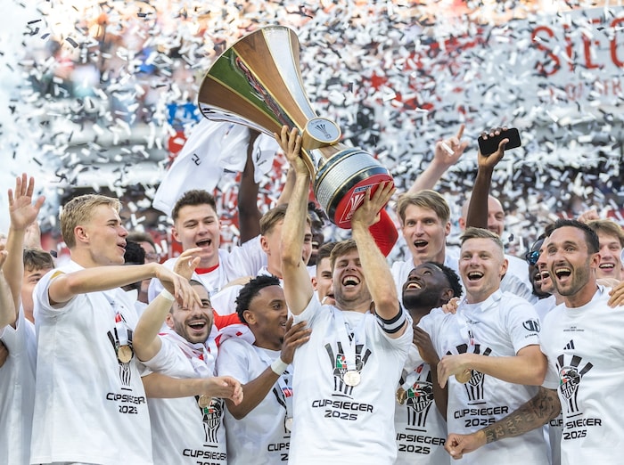 Kapitän Dominik Baumgartner stemmt die Cup-Trophäe in die Höhe, seine Mannschaftskollegen jubeln ...