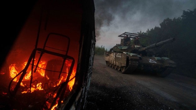 Ein ukrainischer Panzer fährt nahe der russischen Grenze an einem brennenden Fahrzeug vorbei. (Bild: AP/Evgeniy Maloletka)