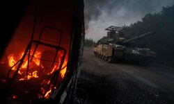 Ein ukrainischer Panzer fährt nahe der russischen Grenze an einem brennenden Fahrzeug vorbei.