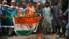 Während eines Protests in Pakistan, bei dem die indischen Angriffe verurteilt werden, wird eine Flagge Indiens verbrannt. (Bild: APA/Associated Press)