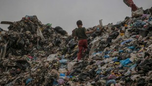 Ein kleines Kind wühlt im Müll.  (Bild: EPA/MOHAMMED SABER)