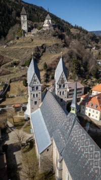 Die Stadtpfarrkirche von Friesach mit ihren zwei mächtigen Türmen, oben am Hügel thronen die Peterskirche und der Wohnturm der Burgruine am Petersberg. (Bild: Arbeiter Dieter)