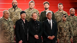 U2-Frontmann Bono, sein Gitarrist „The Edge“ und Hollywood-Star Sean Penn mit ihren „Freunden aus den Schützengräben“ (Bild: AFP/BERTRAND GUAY)