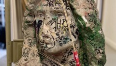 Die Skulptur aus Marmor ist mit zahlreichen Graffiti versehen, Mund und Nase sind abgeschlagen.