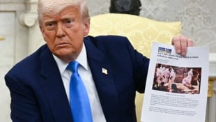Trump hält ein Bild hoch, das gar nicht in Südafrika aufgenommen wurde. (Bild: AFP/JIM WATSON)
