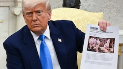 Trump hält ein Bild hoch, das gar nicht in Südafrika aufgenommen wurde. (Bild: AFP/JIM WATSON)