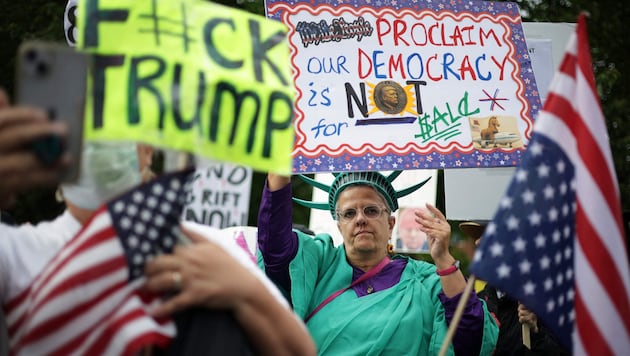 Demonstranten vor dem Golfclub hielten Plakate mit Slogans hoch wie „Stoppt Trumps Krypto-Korruption“ oder „Demokratie steht nicht zum Verkauf“. 