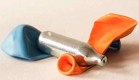 Eine Lachgas-Kapsel und Luftballons – das Rezept für einen kurzen Rausch mit Risiko (Bild: Corinne - stock.adobe.com)