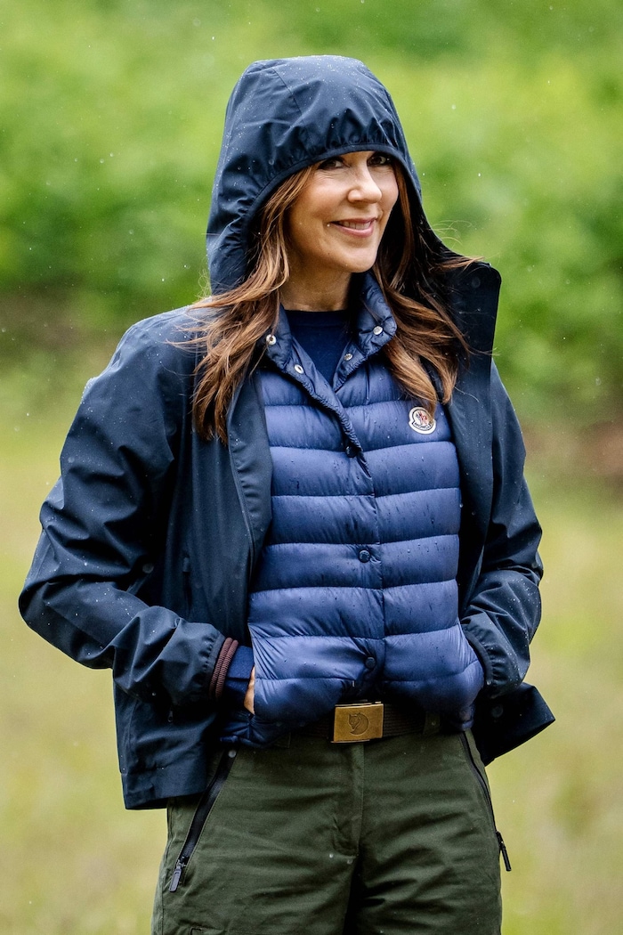 Praktisch und stilvoll: Unter ihrer Regenjacke trägt Mary eine schicke blaue Daunenweste der Luxusmarke Moncler.