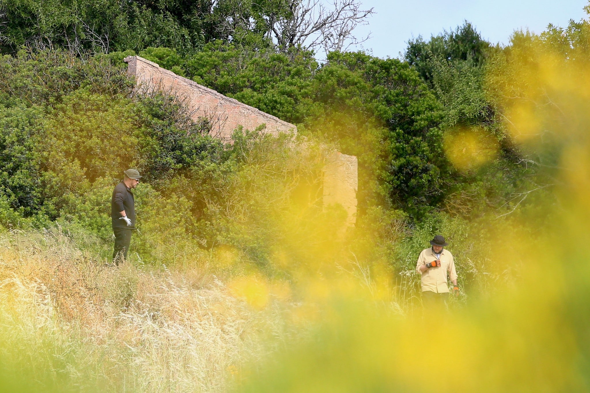 Polizisten durchqueren das unwegsame Gelände rund um ein verlassenes Haus. (Bild: AP/Joao Matos) Polizisten durchqueren das unwegsame Gelände rund um ein verlassenes Haus. (Bild: AP/Joao Matos)