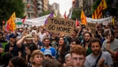 „Geh nach Hause, Tourist“ – eine Demonstrantin hält ein Schild mit eindeutiger Botschaft in den ...