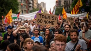 „Geh nach Hause, Tourist“ – eine Demonstrantin hält ein Schild mit eindeutiger Botschaft in den ...