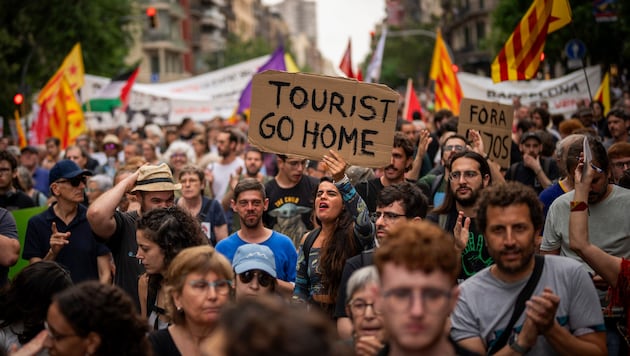 „Geh nach Hause, Tourist“ – eine Demonstrantin hält ein Schild mit eindeutiger Botschaft in den ...