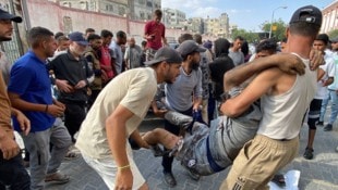 Palästinenser bringen einen Mann, der während der Lebensmittelausgabe von Israelis angeschossen ...