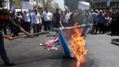 Menschen im Iran verbrennen Flaggen von Israel und den USA.
