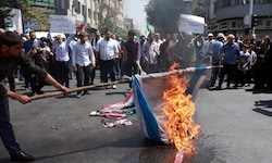 Menschen im Iran verbrennen Flaggen von Israel und den USA.