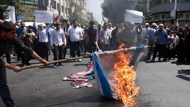 Menschen im Iran verbrennen Flaggen von Israel und den USA.